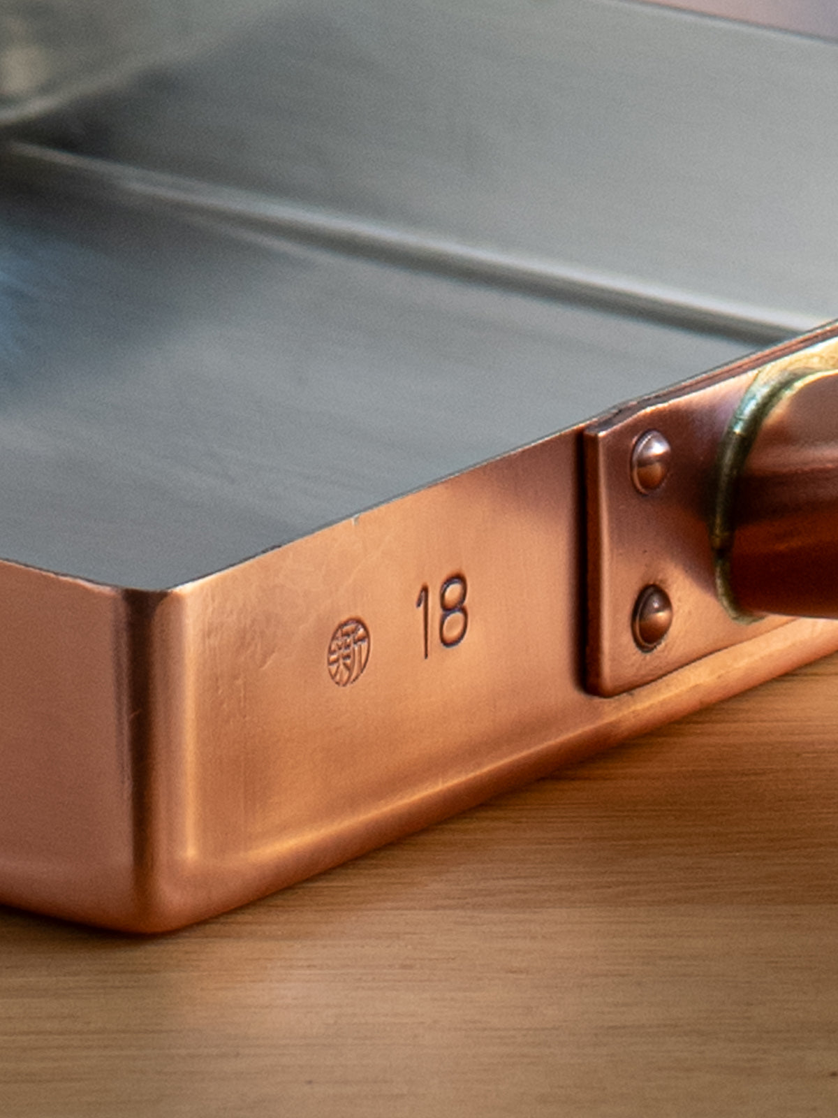 Copper tamagoyaki pan viewed from the side showing the pan's depth and handle