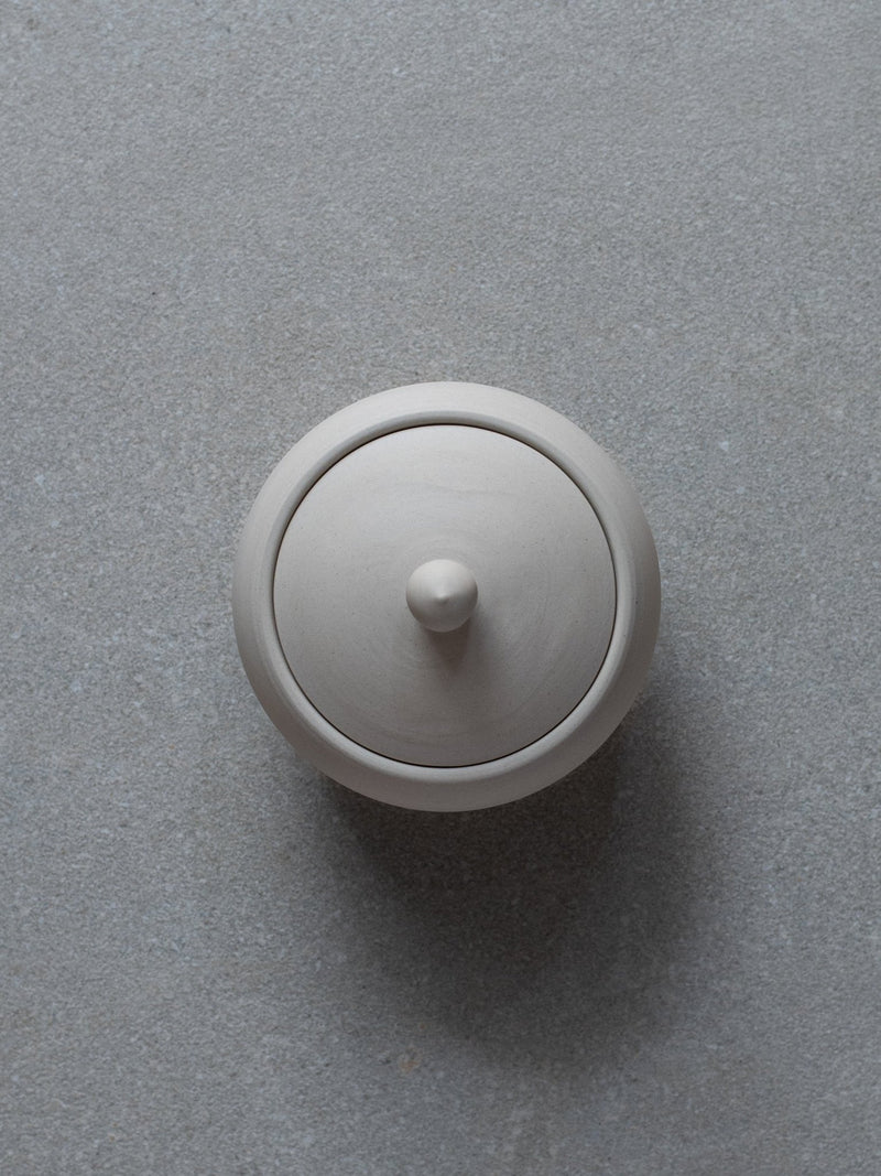 Top view of lidded ceramic pot in natural sand colour on grey background