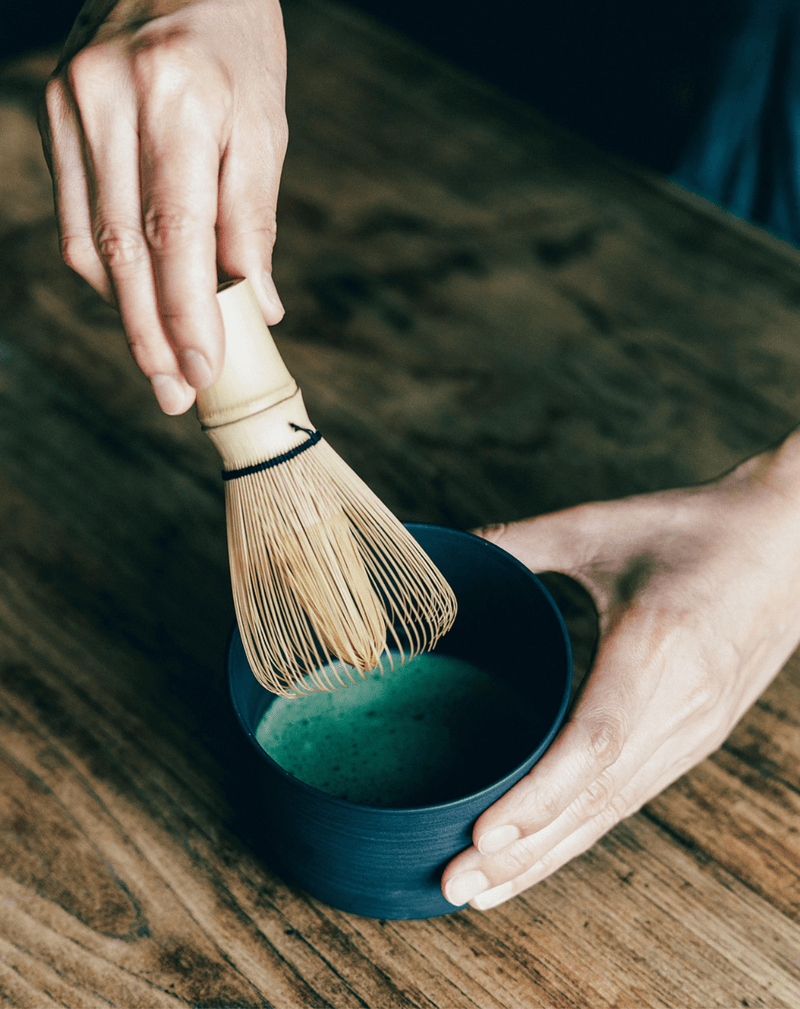 Person whisking matcha in a ceramic matcha bowl made in black clay