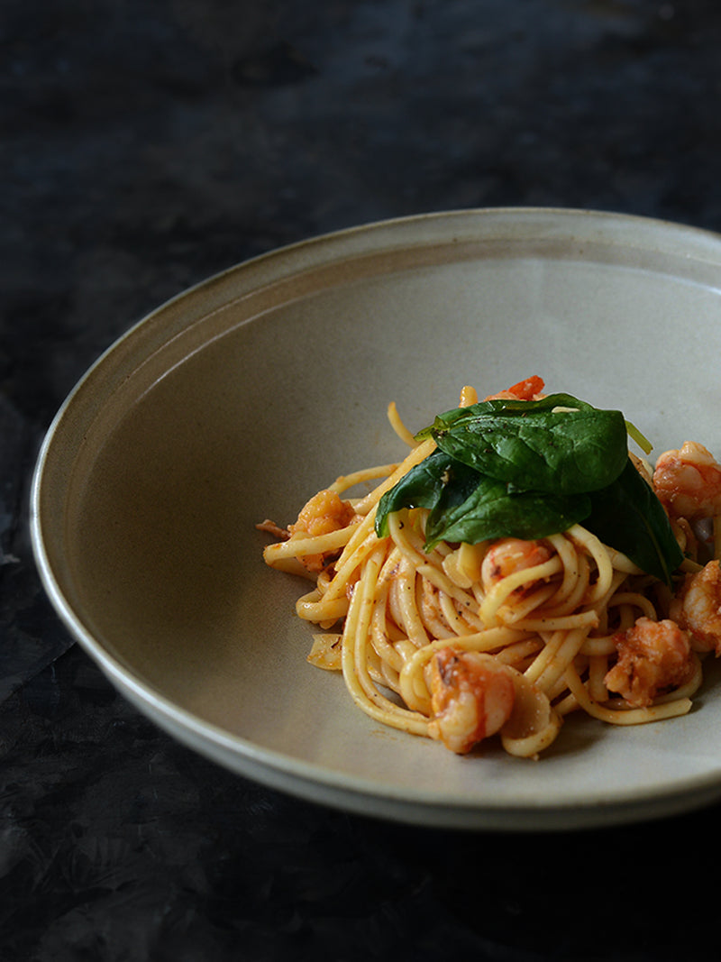 Spaghetti dish with shrimp and spinach on a dark background